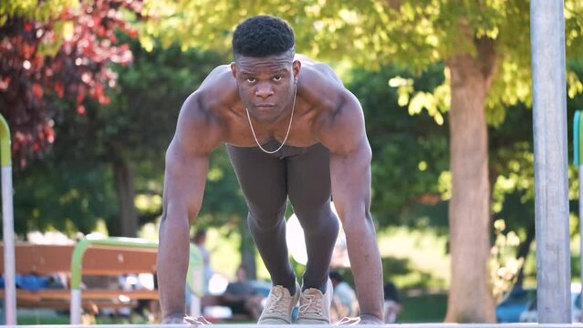 Young fit shirtless black man doing push-ups outdoors on sunny summer day. Fitness and sport lifestyle.