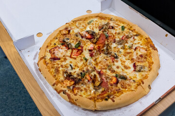 Newcastle England: 14th July 2022: Huge 14 inch spicy chicken tikka pizza from a takeaway. Very greasy in cardboard pizza box