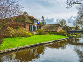 Fototapeta na wymiar Lush green garden and thatched roof Dutch houses in Giethoorn village, Netherlands