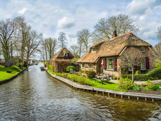 Fototapeta na wymiar Canal side thatched roof houses in the fairy tale village of Giethoorn, Netherlands