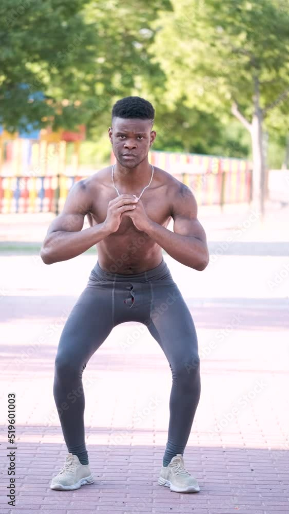 Wall mural Young fit shirtless black man doing squats outdoors on sunny summer day. Fitness and sport lifestyle.