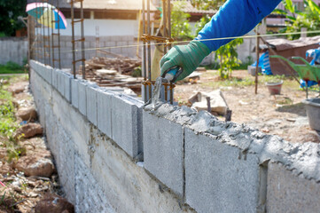 masonry worker make concrete wall by cement block and plaster at construction site