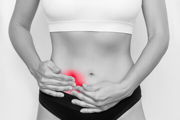 A young woman holding her side with her hands isolated on a white background. Ache in the lower abdomen. Stomach pain. Gynecological problems, cyst, inflammation of the ovary. Black and white
