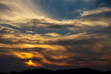 Fototapeta na wymiar 雲に隠れて山の向こうに沈む夕日