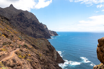 Backpack woman on hiking trail from Afur to Taganana with scenic view of Atlantic Ocean coastline and Anaga mountain range, Tenerife, Canary Islands, Spain, Europe. Looking at Cabezo el Tablero crag