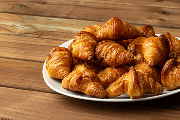 Croissants en plato sobre mesa de madera.
