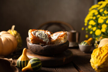 Homemade cinnabons with pumpkin cream and vanila cream on wooden background with raw...