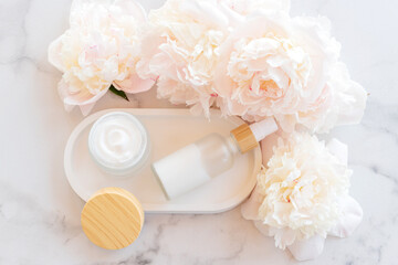 Natural organic cosmetic products with essential peony oil. Skin care cosmetics on concrete tray with flowers.