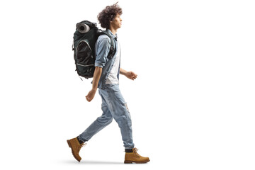 Full length profile of a young male traveler walking with a backpack