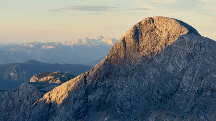 markante Felswand im Abendlicht, Alpenglühen mit hohen Bergen im Hintergrund