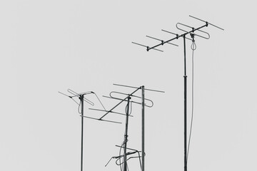 Three old antennas in black and white on a grey background for receiving radio or television signal