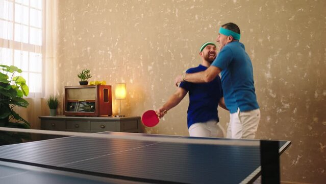 Ping ping time for a group of two men very charismatic and excited playing together the table tennis they hitting and catch the balls with the paddles