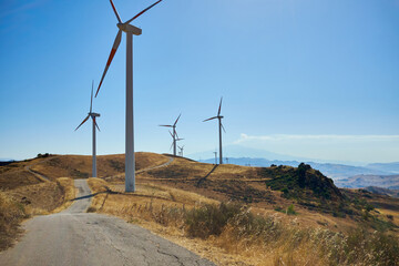 wind turbines on the slopes of the mountains of central Sicily with the Etna volcano at the bottom in the morning lights