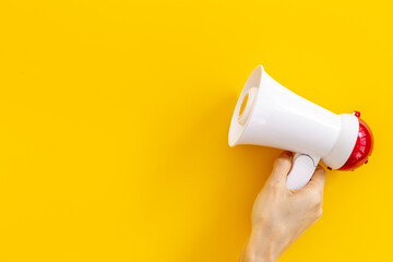 Hand holding megaphone against the empty wall. Hiring or advertising concept