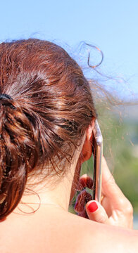 An Adult Woman Talking On The Phone Was Photographed From Behind