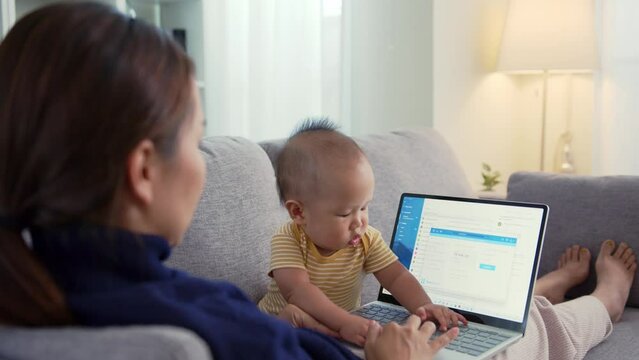 Asian baby disturb mother during using laptop computer at home