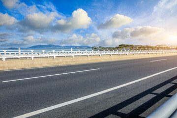 Asphalt road and river with mountain nature landscape under blue sky