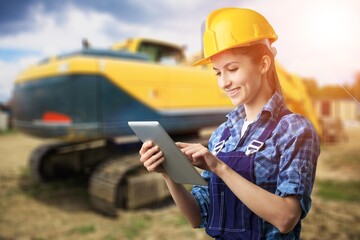 Cheerful female excavator operator on construction site. Woman construction apprentice drive heavy equipment