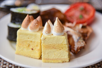 Cream cakes and other food on plate. Western Buffet in restaurant.