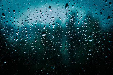 Drops of rain on glass with filter effect retro vintage style. Raindrops on window glass. Selective focus. Rainy city background. Wet glass view of park autumn, abstract background drops on the glass.