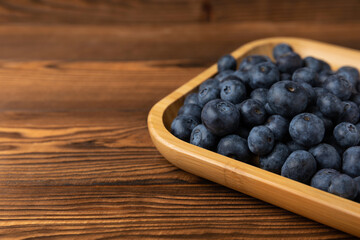Blueberries in a bowl on a brown textured background. Ripe and fresh blueberries. Vitamins. Healthy food. Juicy berry. Copy space. Place for text