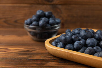 Blueberries in a bowl on a brown textured background. Ripe and fresh blueberries. Vitamins. Healthy food. Juicy berry. Copy space. Place for text