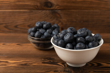 Blueberries in a bowl on a brown textured background. Ripe and fresh blueberries. Vitamins. Healthy food. Juicy berry. Copy space. Place for text