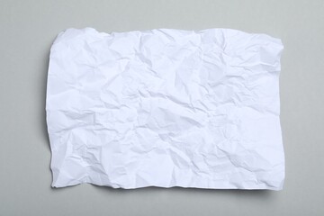 Obraz premium Sheet of white crumpled paper on grey background, top view