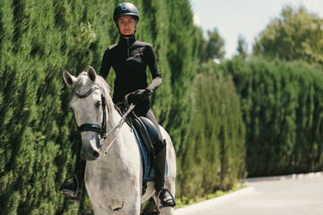 Equestrian sport. Portrait of young woman, female rider training at riding arena in summer day,...
