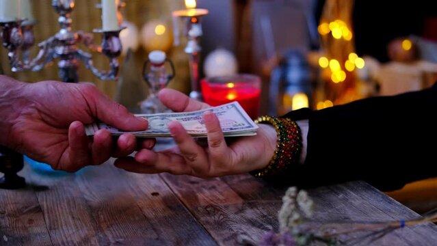 Librate with money over male client's hand, oracle foretelling, Female Fortuneteller or esoteric Oracle performs ritual of removing spell of black magic, esoteric business, magic to increase income