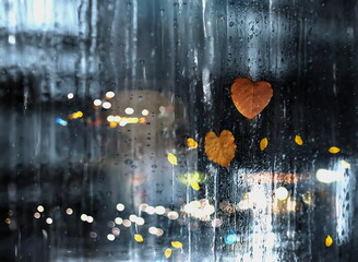 rain in  city street, people silhouette with umbrellas ,modern building ,Rainy weather season ,Autumn leaves on window,wet drops ,night  blurred light  reflection cold urban  defocus   background 