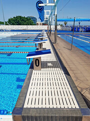 Perspective view of competition pool lanes with floating lanes and start block. Water sport,...