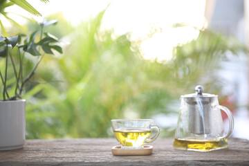 Tea in glass cup and tea pot on wooden table with nature view