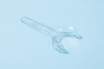 Retractor Dental lip retractor Access to the oral cavity. Wide mouth opening for a dental procedure on a clean blue background