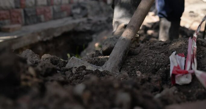 Cinematic close up shot of farmer digging ground with shovel 