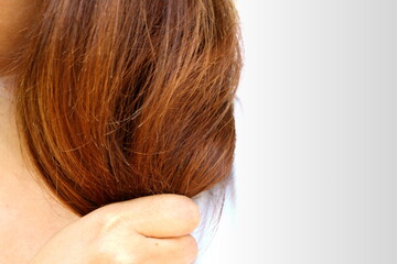 Asia woman wear white shirt holding her long hairs that make color treatments that maybe reason make hairs have problem (split end) .Should care or cut end of hairs. On plain background