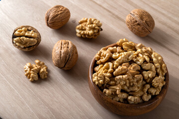 Peeled walnuts and whole walnuts on wooden background