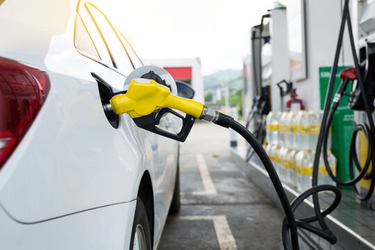 Transportation and ownership concept - man pumping gasoline fuel in car at gas station. hight price during war concept.