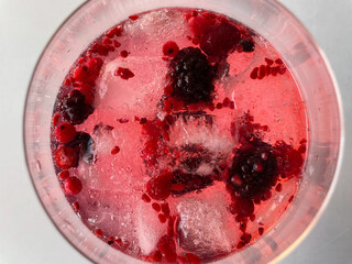 Gin tonic with ice and red berries seen from above