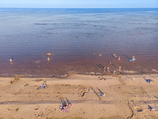 Fototapeta na wymiar People sunbathe and swim in the lake. Bird's-eye view.