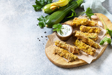 Healthy tasty snack, summer food. Zucchini fries. Crispy Zucchini sticks in breadcrumbs, with cheese with garlic yogurt sause. Copy space.