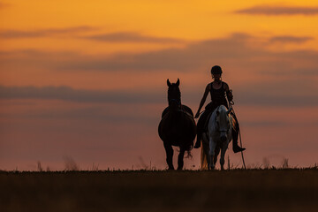 she rides her horse off into the orange sunset and leads another horse on a rope