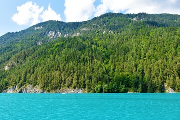 Forest covered mountains in Gailtal Alps in Carinthia, Austria and turquoise colored Weissensee lake bellow