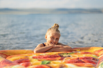 girl bathes in the lake on a mattress