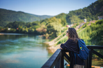 Young woman traveler admiring green hills and Drina river while traveling in Serbia at summer