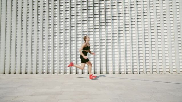 Cinematic action footage of a sport woman training and doing fitness exercises outdoor in an urban area of the city. Concept about running and active functional workouts