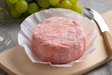 Le rose, pink soft French cheese with cow’s milk and refined with rosé champagne close up on a cutting board 