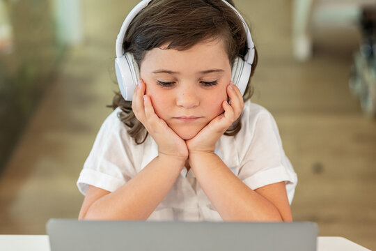 Girl with a bored face sitting in front of a laptop