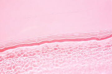 Background, texture of transparent pink water with seething ripples , waves