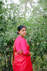 South asian newly married housewife in traditional red shari, religious women in outdoor environment  